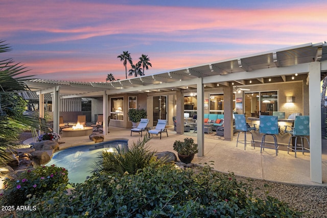 patio terrace at dusk featuring an outdoor living space with a fire pit and a pergola