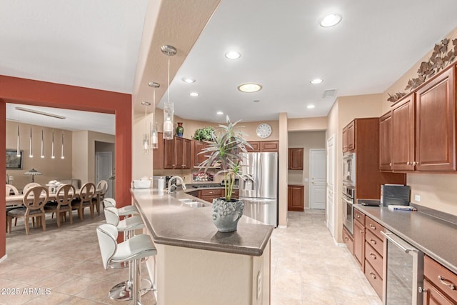 kitchen with visible vents, wine cooler, a kitchen bar, a sink, and stainless steel appliances