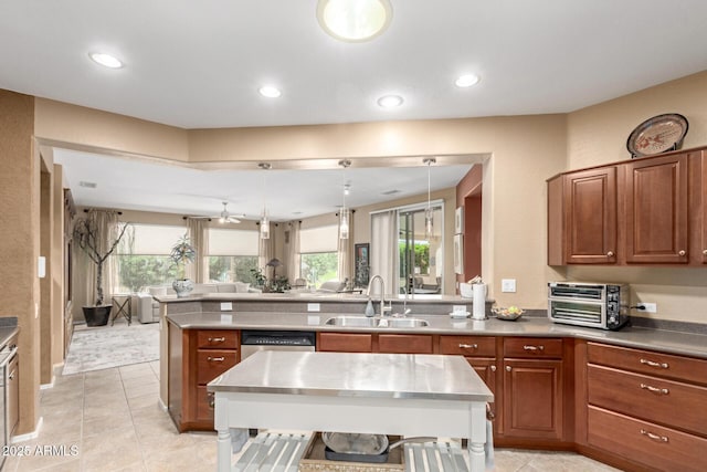 kitchen featuring brown cabinetry, a sink, a toaster, a peninsula, and recessed lighting