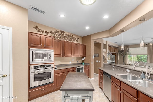 kitchen with a sink, appliances with stainless steel finishes, brown cabinets, and visible vents