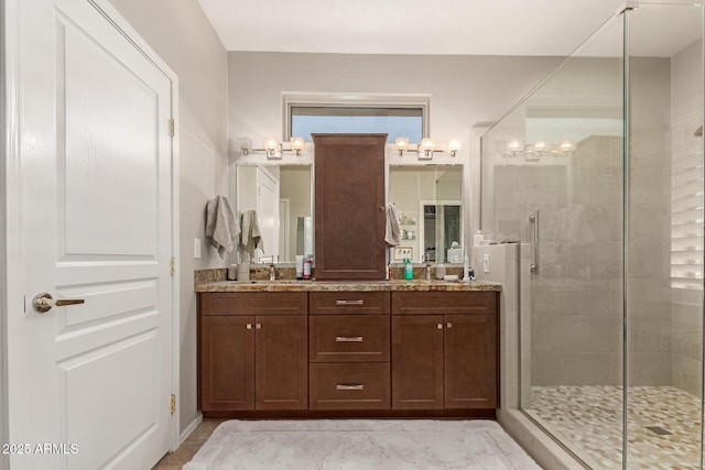 full bathroom featuring vanity, a notable chandelier, and a shower stall