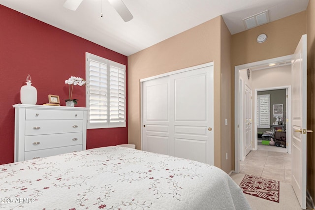 bedroom with visible vents, ceiling fan, light tile patterned flooring, and a closet