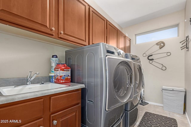clothes washing area with a sink, cabinet space, light tile patterned floors, and washer and clothes dryer