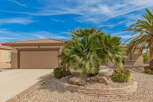 view of front facade with an attached garage, stucco siding, concrete driveway, and a tiled roof