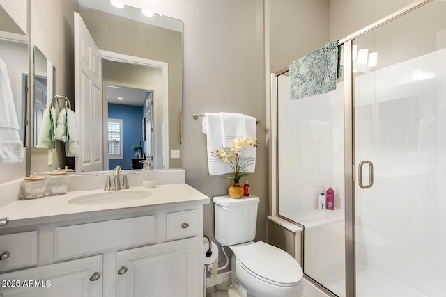 bathroom featuring a shower stall, toilet, and vanity