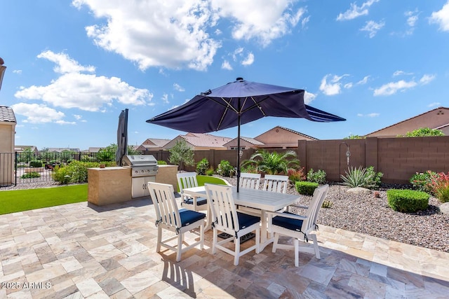 view of patio / terrace with exterior kitchen, outdoor dining area, a fenced backyard, and grilling area