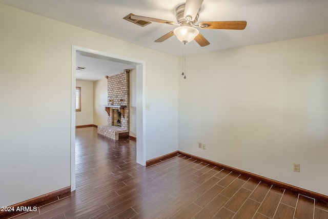 unfurnished room with ceiling fan and a fireplace