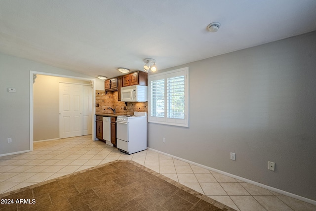 kitchen with tasteful backsplash, light tile patterned flooring, vaulted ceiling, and white appliances