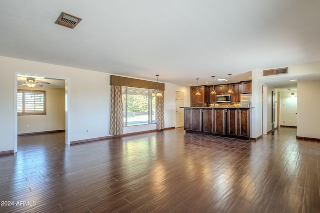 unfurnished living room featuring ceiling fan and dark hardwood / wood-style flooring