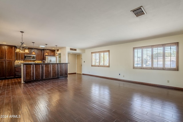 unfurnished living room with dark hardwood / wood-style flooring and a chandelier