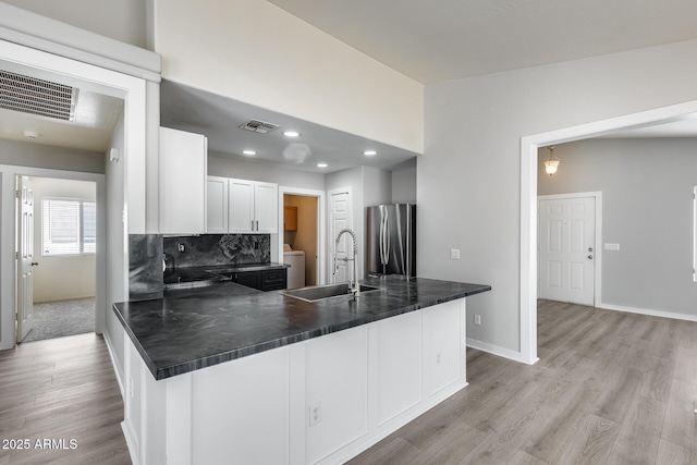 kitchen featuring a sink, visible vents, dark countertops, and freestanding refrigerator