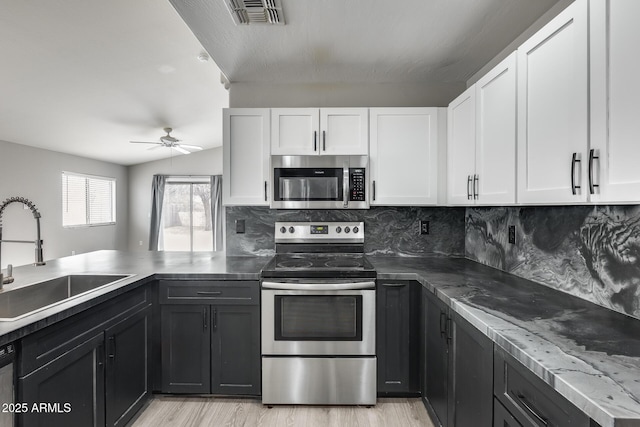 kitchen with a sink, appliances with stainless steel finishes, white cabinets, and ceiling fan