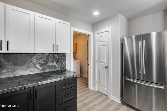 kitchen featuring light wood-style flooring, tasteful backsplash, freestanding refrigerator, white cabinets, and dark cabinets