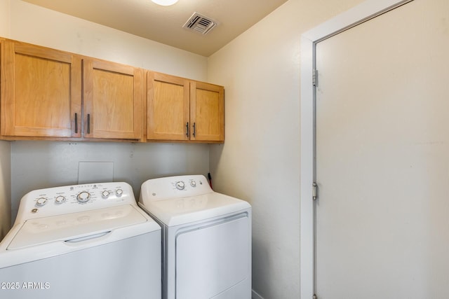 washroom with visible vents, cabinet space, and washing machine and dryer