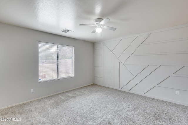 carpeted empty room featuring a textured ceiling, visible vents, and ceiling fan