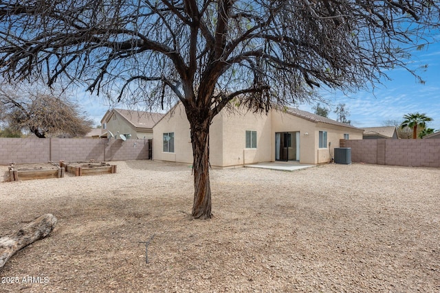 back of property with stucco siding, a vegetable garden, a fenced backyard, and a patio area