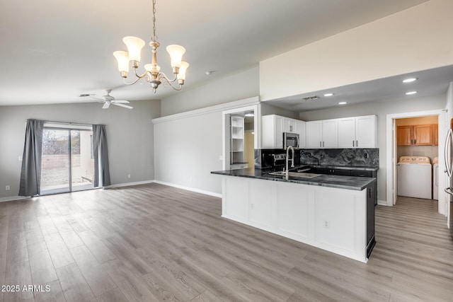 kitchen with dark countertops, stainless steel microwave, decorative backsplash, washer / clothes dryer, and a sink