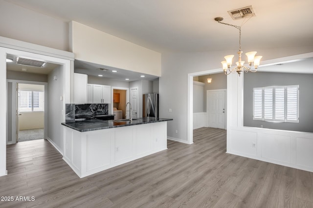 kitchen with a sink, visible vents, lofted ceiling, and freestanding refrigerator