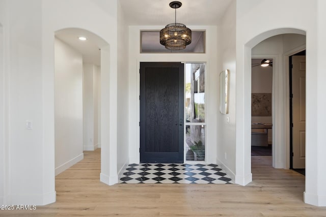foyer with baseboards, arched walkways, and wood finished floors