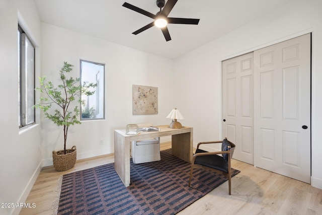 office space featuring light wood-style floors, a ceiling fan, and baseboards