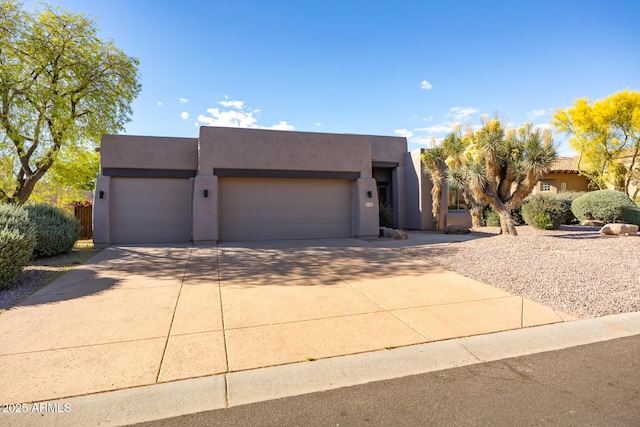 pueblo-style home with a garage, driveway, and stucco siding