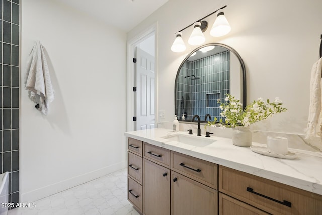 bathroom featuring a tile shower, vanity, and baseboards
