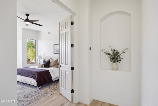 bedroom featuring light wood finished floors, baseboards, and a ceiling fan