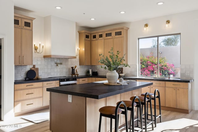 kitchen featuring dark countertops, light wood-type flooring, a kitchen breakfast bar, and recessed lighting