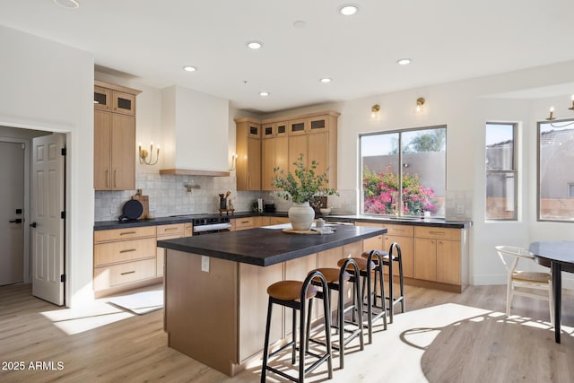 kitchen with dark countertops, electric range, light wood-type flooring, a kitchen breakfast bar, and recessed lighting