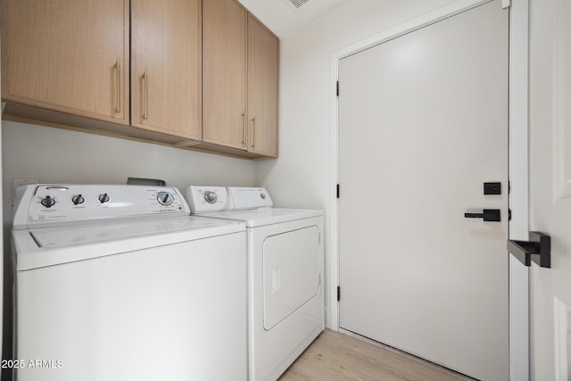 washroom featuring cabinet space, washer and dryer, and light wood-style floors