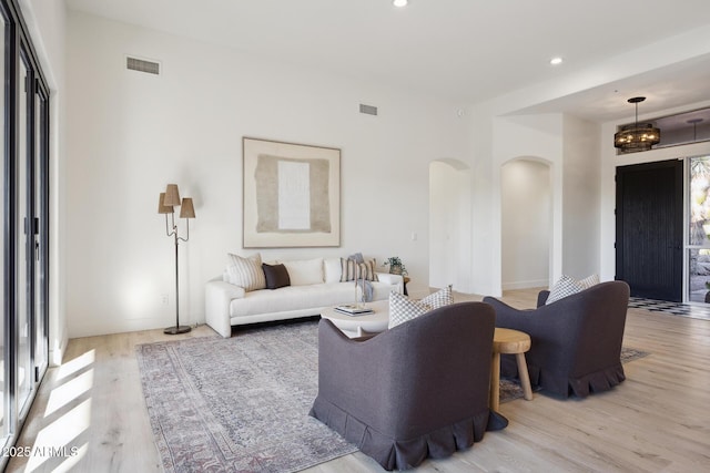 living room featuring arched walkways, light wood finished floors, recessed lighting, and baseboards