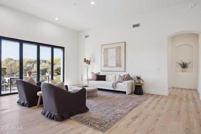 living area featuring wood finished floors, arched walkways, recessed lighting, and baseboards