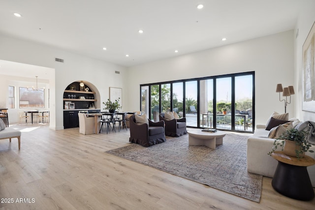living room featuring recessed lighting, built in features, a chandelier, and light wood-style floors