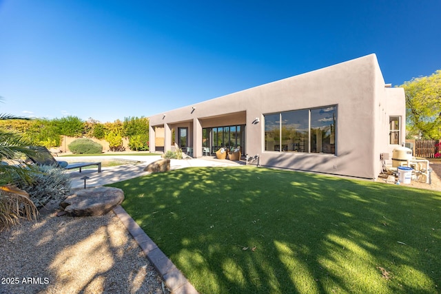 back of property with stucco siding and a lawn