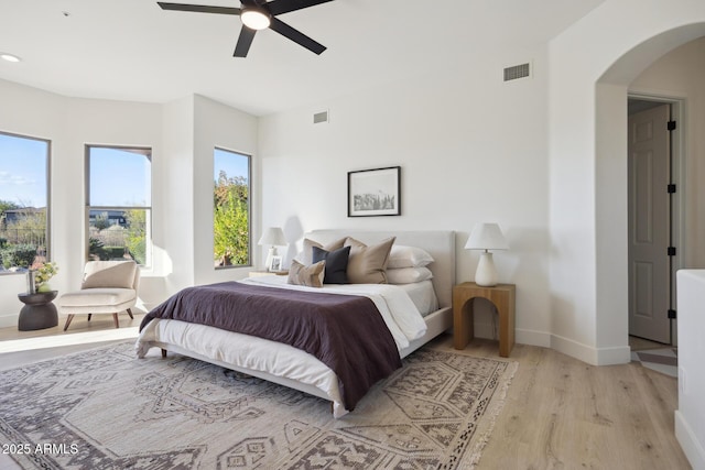 bedroom featuring light wood-style floors, arched walkways, baseboards, recessed lighting, and a ceiling fan