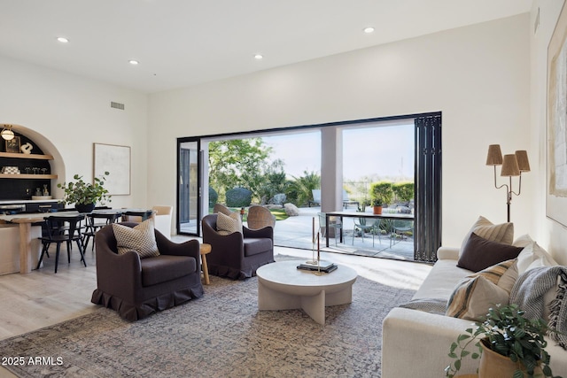 living room with recessed lighting, light wood finished floors, and a towering ceiling
