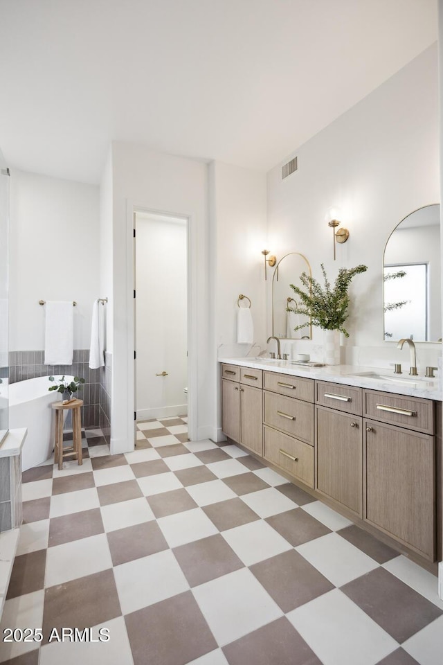 full bath featuring double vanity, tile patterned floors, and a freestanding bath