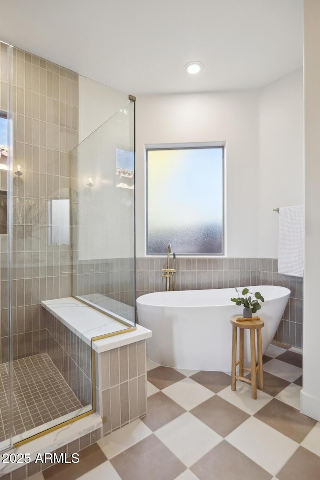 full bathroom with tile walls, a stall shower, a freestanding bath, recessed lighting, and wainscoting