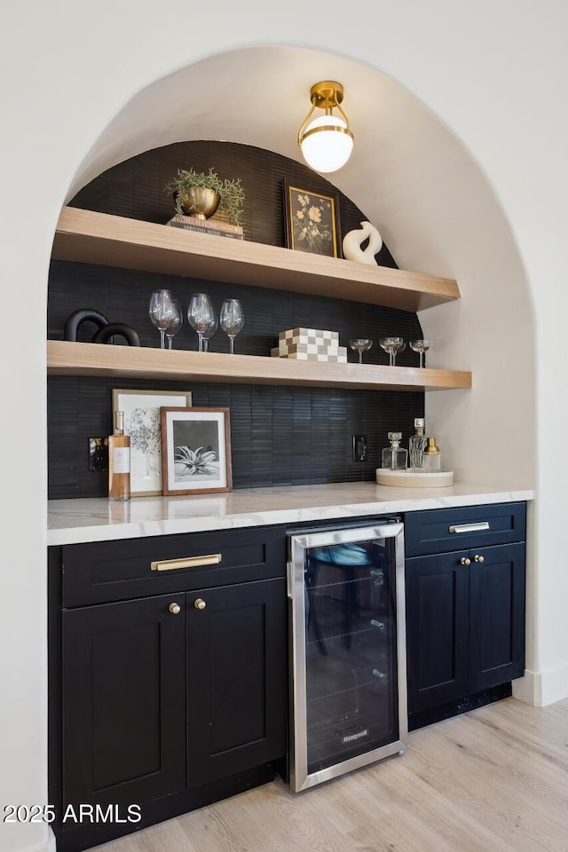 indoor dry bar featuring wine cooler, light wood-type flooring, and tasteful backsplash