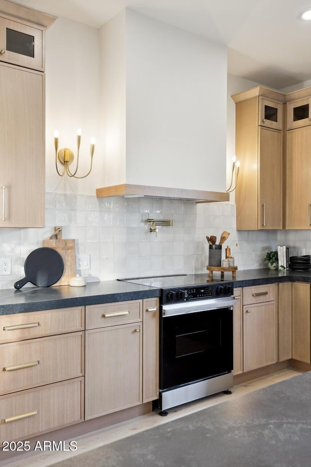 kitchen featuring electric range, light brown cabinets, and dark countertops