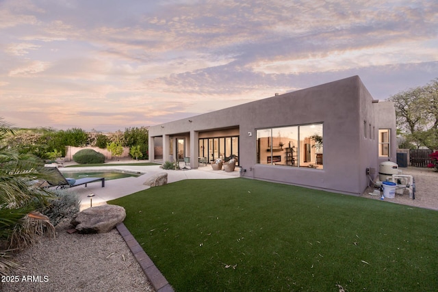 back of property at dusk with a patio area, an outdoor pool, and stucco siding