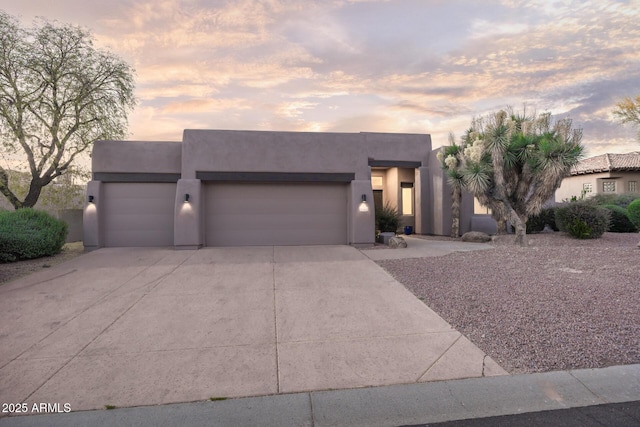southwest-style home with an attached garage, driveway, and stucco siding