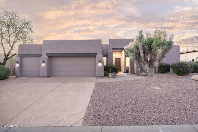 pueblo revival-style home with a garage, concrete driveway, and stucco siding