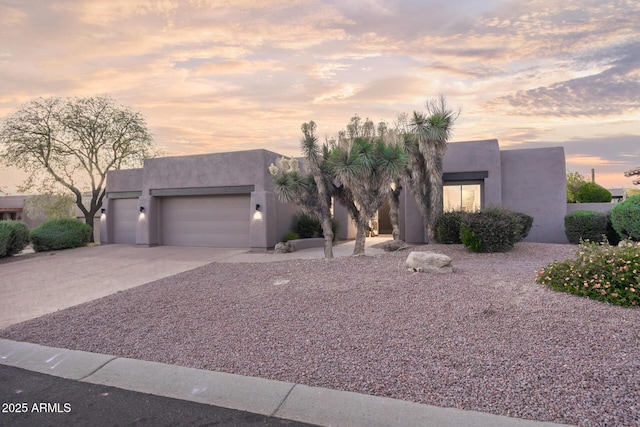 southwest-style home featuring stucco siding, concrete driveway, and an attached garage