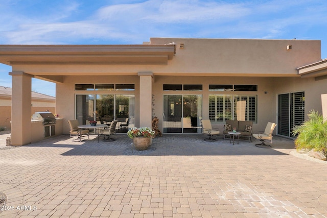 back of property with an outdoor hangout area, exterior kitchen, a patio area, and stucco siding