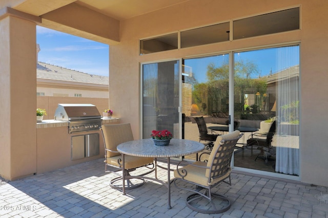 view of patio / terrace featuring exterior kitchen, outdoor dining area, and a grill