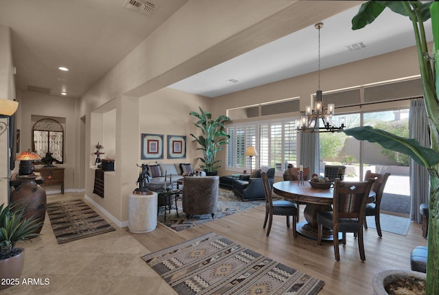 dining room with light wood-style floors, baseboards, visible vents, and a chandelier