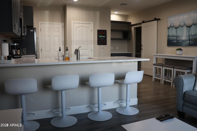 kitchen with kitchen peninsula, dark hardwood / wood-style flooring, and a barn door