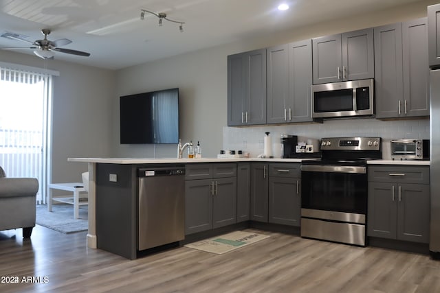 kitchen featuring gray cabinets, kitchen peninsula, and appliances with stainless steel finishes