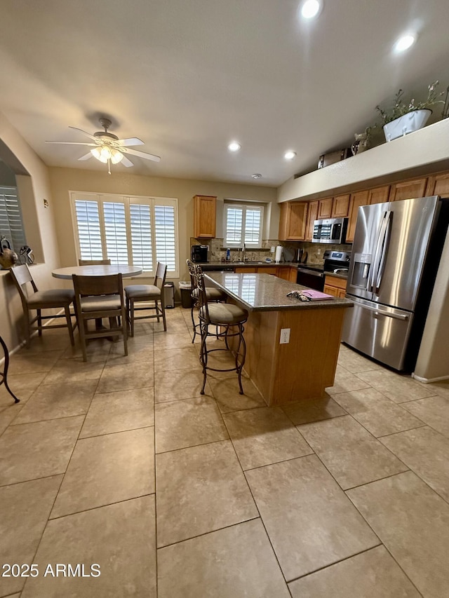 3891 E Simpson Rd, Gilbert, AZ 85297 - kitchen with appliances with stainless steel finishes, a center island, ceiling fan, decorative backsplash, and recessed lighting